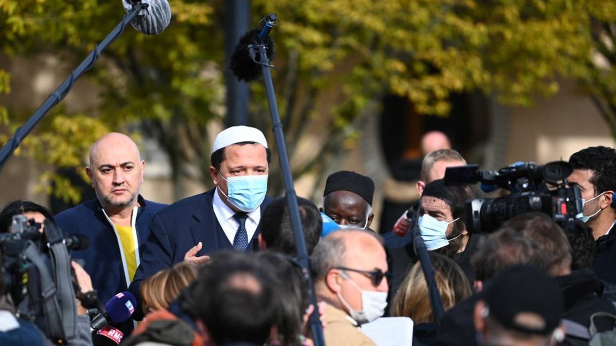 L'imam de Drancy, Hassan Chalghoumi (masque sanitaire, au milieu) et l'écrivain Marek Halter (à sa droite) s'adressent à la presse devant le lycée du Bois d'Aulne, le 19 octobre 2020, à Conflans-Sainte-Honorine, au nord-ouest de Paris. 
